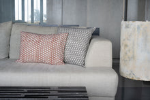 Load image into Gallery viewer, Hand block printed Terracotta cotton lumbar cushion cover placed next to a grey hand block printed cushion cover on a couch
