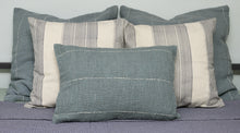 Load image into Gallery viewer, Hand woven feather blue coloured lumbar cotton cushion cover styled alongside cotton sham cushion covers on a bed
