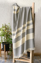 Load image into Gallery viewer, Hand woven woollen grey and ivory throw blanket placed on a prop for a mood shot
